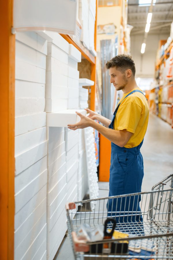 Male builder choosing insulation for the walls in hardware store. Customer look at the goods in diy shop